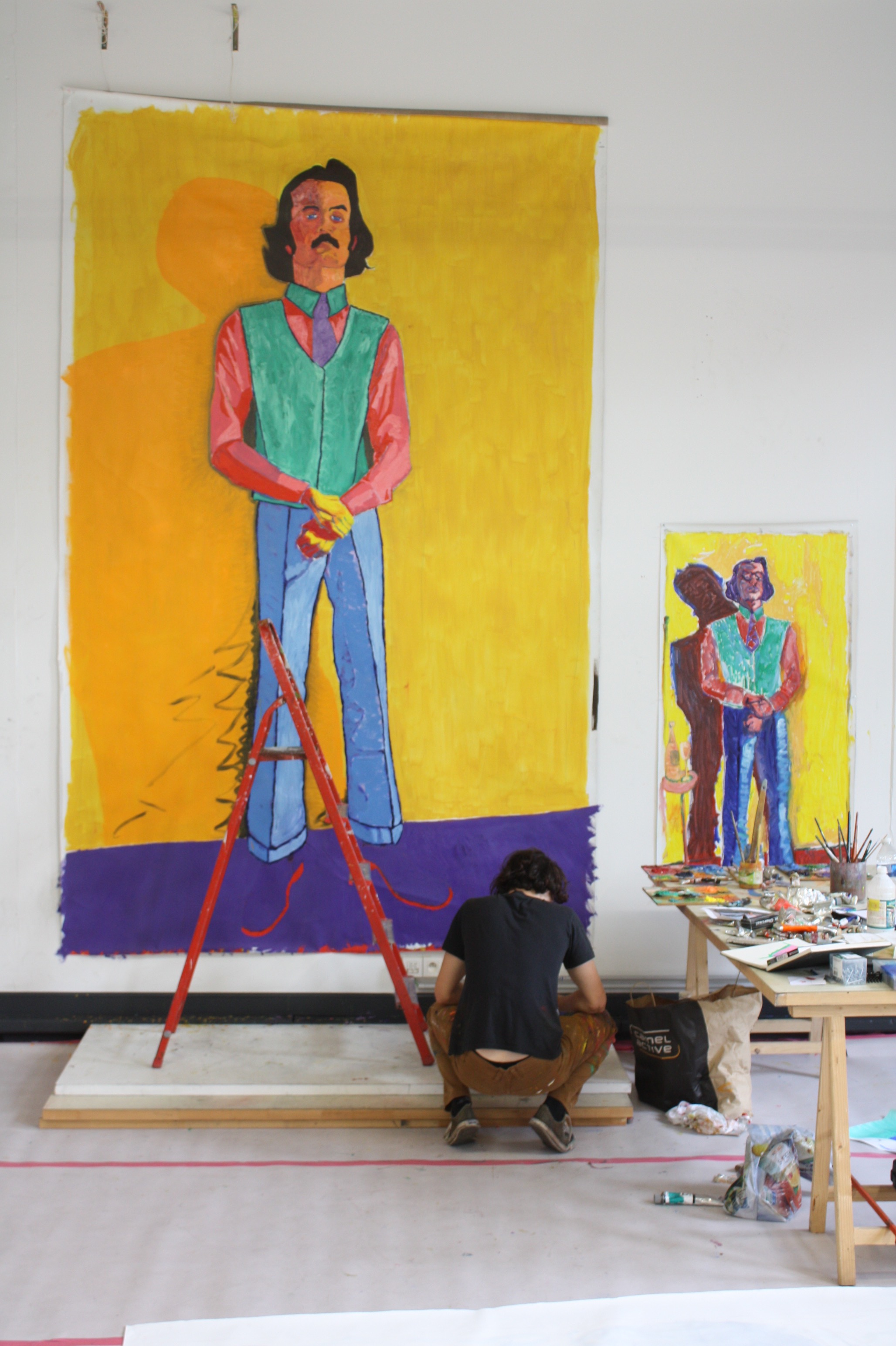 Vic aan het werk aan een metersgroot zelfportret, staand met felle kleuren.